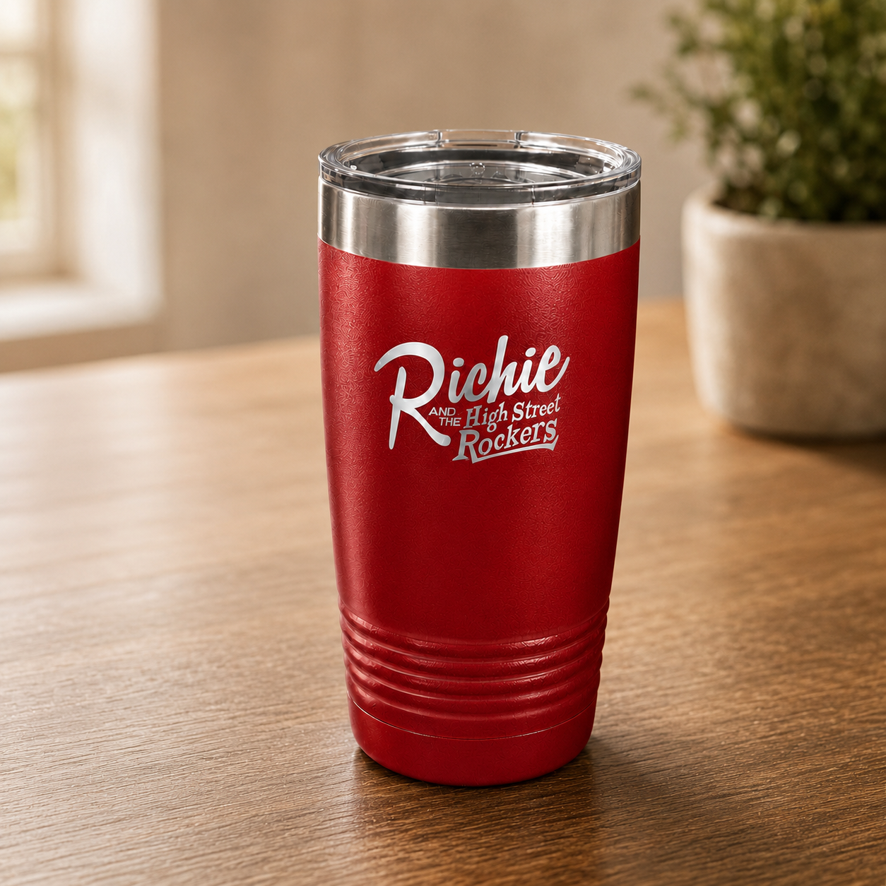 Red insulated tumbler with 'Richie and the High Street Rockers' logo on a wooden surface.